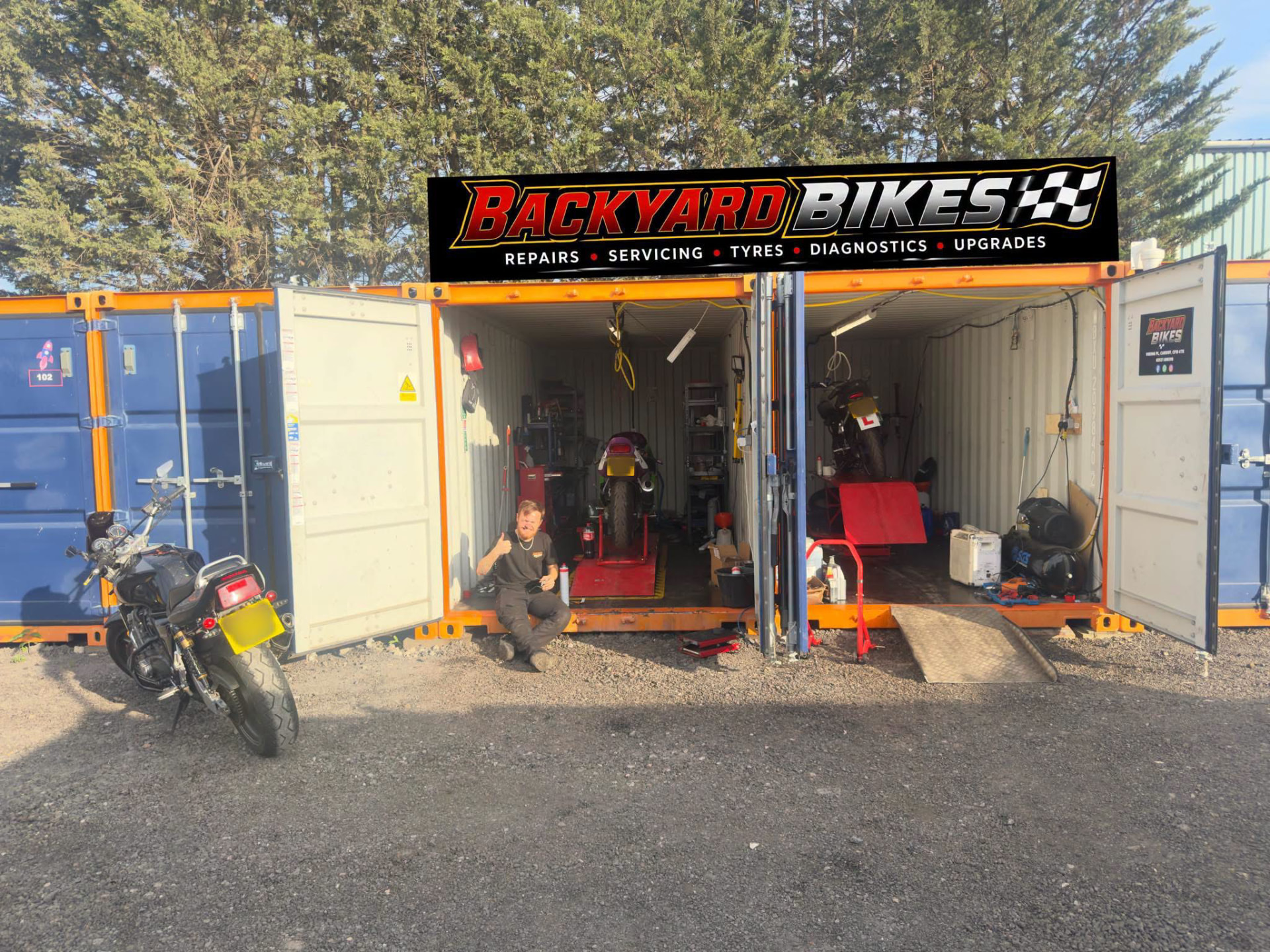 Backyard Bikes workshop shipping containers with a motorcycle out front in Cardiff